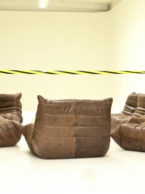 Leather couches placed in empty room under bright striped barrier tape during renovation process