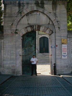 Security guard standing at arched gates of historic building